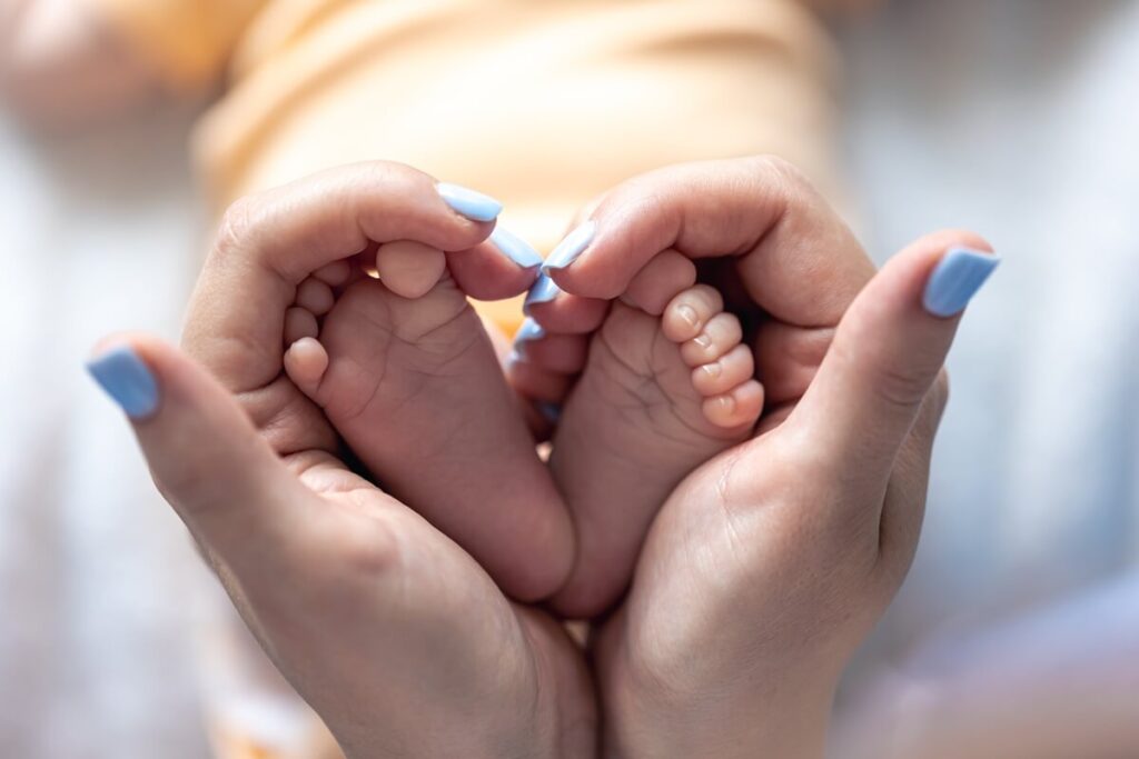 mom holds legs newborn baby her hands